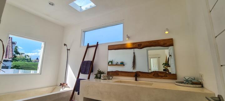 Bathroom with a stone basin, teak mirror and skylight