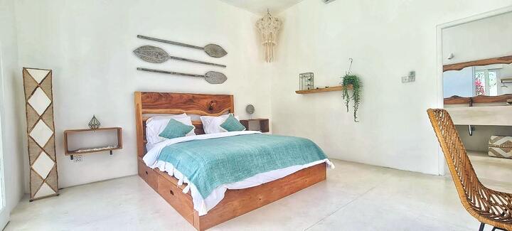 Queen bedroom with a teal throw and teak headboard