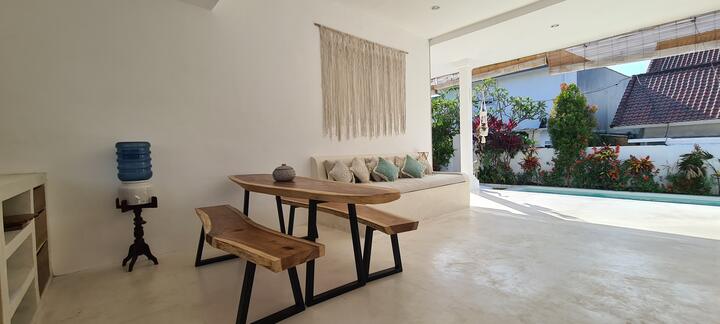 Dining table and sofa in the living room, opening straight out to the pool and garden